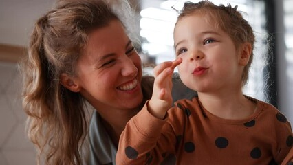 Wall Mural - Happy young mother with little daughter in kitchen eating together at home.