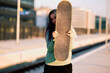 © chika_milan - An urban teenage girl standing at the train station and holding skateboard. Teenage skater girl holding the board.