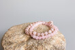 Two bracelets made of natural pink quartz stones beads isolated on pastel beige background. Handmade jewelry. Woman exoteric accessories. Talismans and amulets. Selective focus