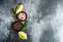 Overhead View Of Bowls With Pink Himalayan Salt, Peppercorns, Rosemary And Lemon Slices