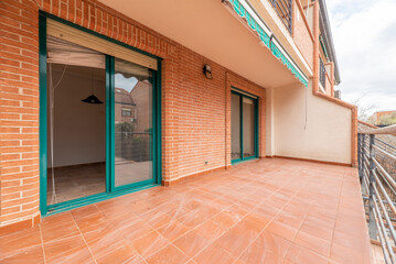 Terrace of a single-family home with a porch and green aluminum and glass sliding windows