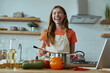 © gstockstudio - Happy young woman cooking soup and smiling while standing at the domestic kitchen