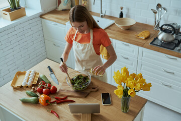 Top view of beautiful young woman cooking at the domestic kitchen