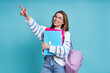 © gstockstudio - Happy female student pointing away while standing against blue background