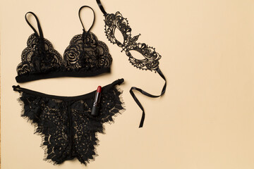 Set of black sexy lace lingerie with accessories on color background, top view