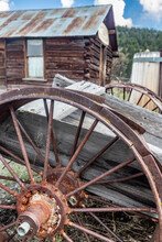 Old Rusty Wheel On Cart With Log Cabin In Background