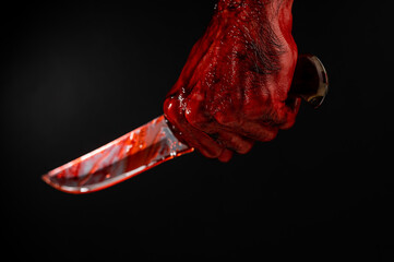 Fototapeta a man with bloody hands brandishes a knife on a black background. 