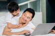 © Creativa Images - Little boy embracing his father while using laptop