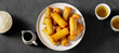 Plate with tasty fried spring rolls on dark background