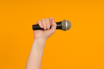 Wall Mural - microphone in hand on a colored background