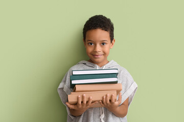 Poster - Little African-American boy with stack of books on green background