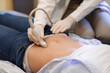 © Pixel-Shot - Young pregnant woman undergoing ultrasound scan in modern clinic