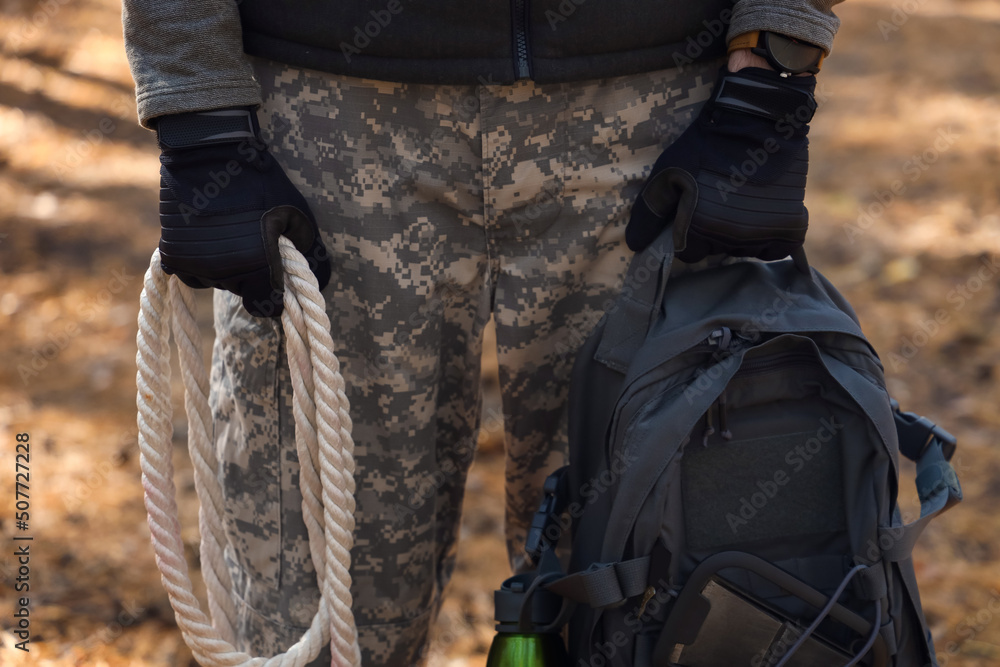 Male tourist with backpack and rope in forest, closeup