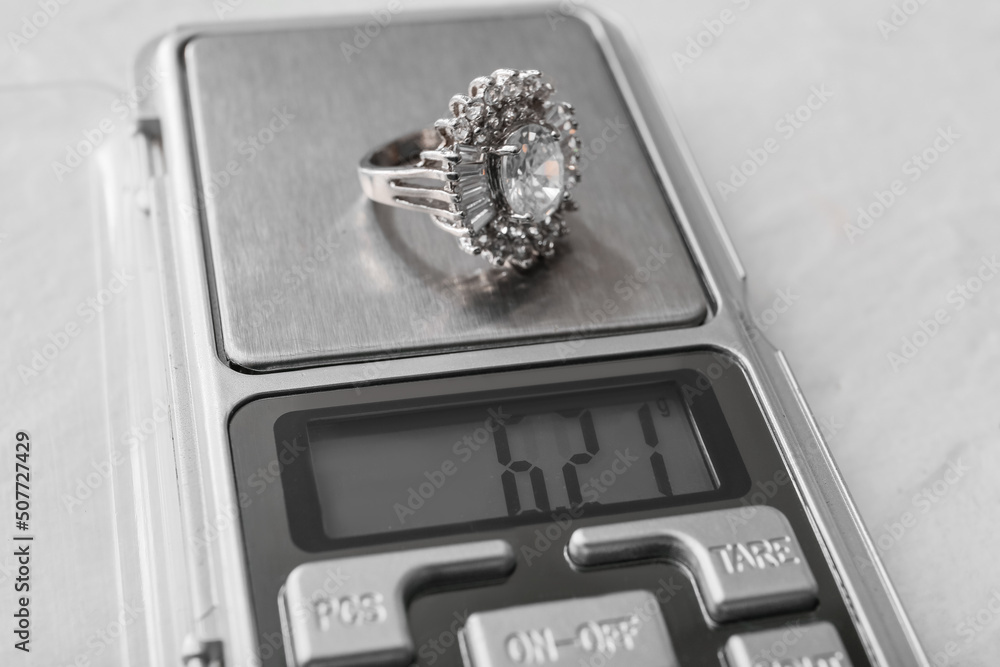 Jewelry scales with ring on white background, closeup