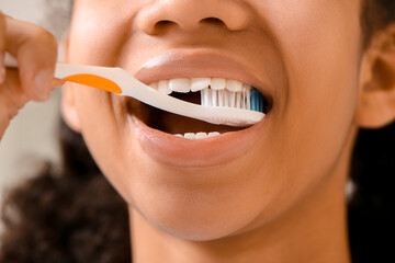 Sticker - African-American teenage girl brushing teeth in bathroom, closeup