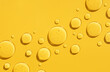round drops of transparent gel serum on a yellow background