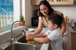 Little boy rinsing fruits under tap water under control on his mother
