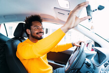 Smiling Man Adjusting Rear-view Mirror In Car