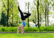 Young Woman Practicing Handstand At Park