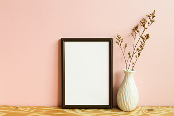 Wall Mural - Picture frame and dry flowers on wooden table. pink wall background. copy space