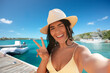 © Syda Productions - people, summer and swimwear concept - happy smiling woman in bikini swimsuit and straw hat taking selfie and showing peace gesture over pier and boat or tropical sea background in french polynesia