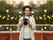 © Syda Productions - photography, profession and people and concept - happy smiling man or photographer in glasses with digital camera over party lights on roof top background