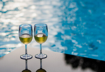 Two glasses of white wine put on table at swimming pool for Holiday and summer drink concept.