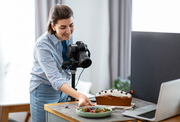 Poster - blogging, profession and people concept - happy smiling female food photographer with camera photographing cake in kitchen at home