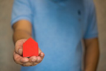 Poster - Hand holds the red house. The concept of a premium house