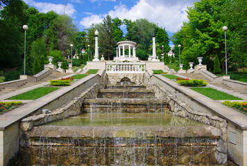 Wall Mural - Moldova, Kishinev. 05.24.2022. View of a white gazebo with columns and water flowing down the steps.