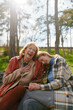 © chika_milan - A grandmother is laughing and having fun with her adolescent granddaughter while sitting on the park bench.