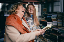 A Grandmother And Granddaughter Choosing Books At Bookstore.