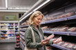© ReeldealHD images - Mid adult female comparing products whilst shopping in a grocery store