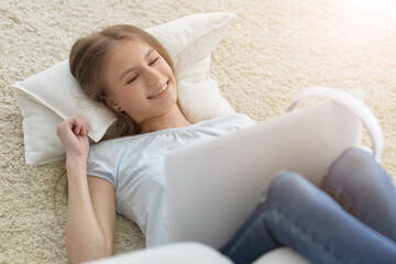 Cute girl using laptop while lying at home