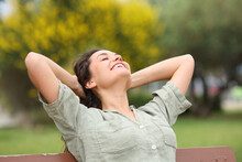 Happy Woman Relaxing In A Park On A Bench