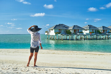 Wall Mural - Paradise beaches of the Maldives. Tourism, travel and vacation in a luxury resort. Woman in bikini on the background of the sea and the beach