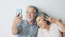 Senior Couple Using A Smart Phone Computer Face Time Call To Relatives Descendant Relatives Grandchild, Smiling Feel Happy In Bed Room Morning At Home - Lifestyle Senior Elderly Concept