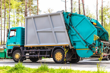 Fototapete - A garbage truck picks up garbage in a residential area. Loading mussar in containers into the car. Separate collection and disposal of garbage. Garbage collection vehicle.