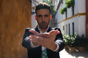 young and handsome gipsy man, dressed in black and white shirt showing 2 hands to camera and selective focus on man's face. Flamenco cultural heritage of humanity.