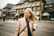 © Maskot - Businesswoman looking away while holding disposable coffee cup in city