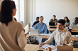 © Maskot - Multiracial students attending lecture in classroom at university