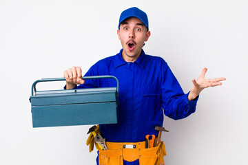 young hispanic plumber amazed, shocked and astonished with an unbelievable surprise. toolbox concept