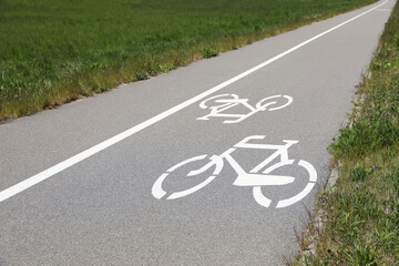 Wall Mural - Bicycle lane with white sign painted on asphalt near sidewalk