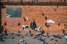 Beautiful Asian Woman Walking Through Flock Of Pigeon Flying In Tha Phae Gate Landmark