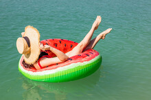 Beautiful Woman Floating On Inflatable Ring In Blue Lake Water