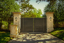 Closed Impressive Wrought Iron Luxury  Security Gate With Key Pad For Private Residential Estate In Leafy Neighborhood With Green Trees And Shadows On Drive