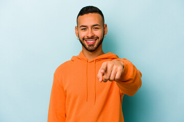 Wall Mural - Young hispanic man isolated on blue background cheerful smiles pointing to front.