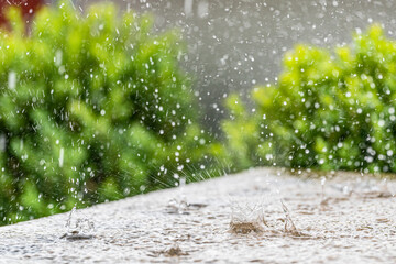 Heavy rain on a sunny summer day. Summer thunderstorms on the terrace stone table