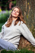 © wernerimages - blond woman sitting outdoors at a tree with eyes closed