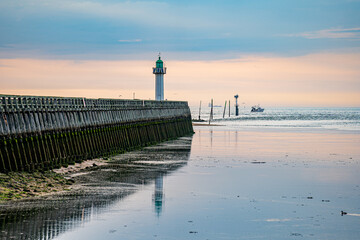 Lighthouse at the entrance to the harbor on the coast of Normandy in France.